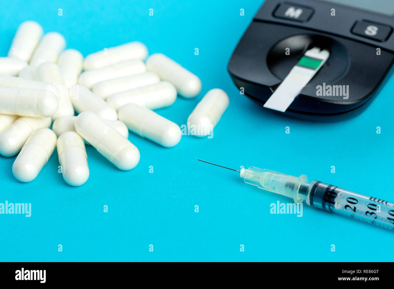 Glucometer, medication, syringe lie on a blue background. Stock Photo