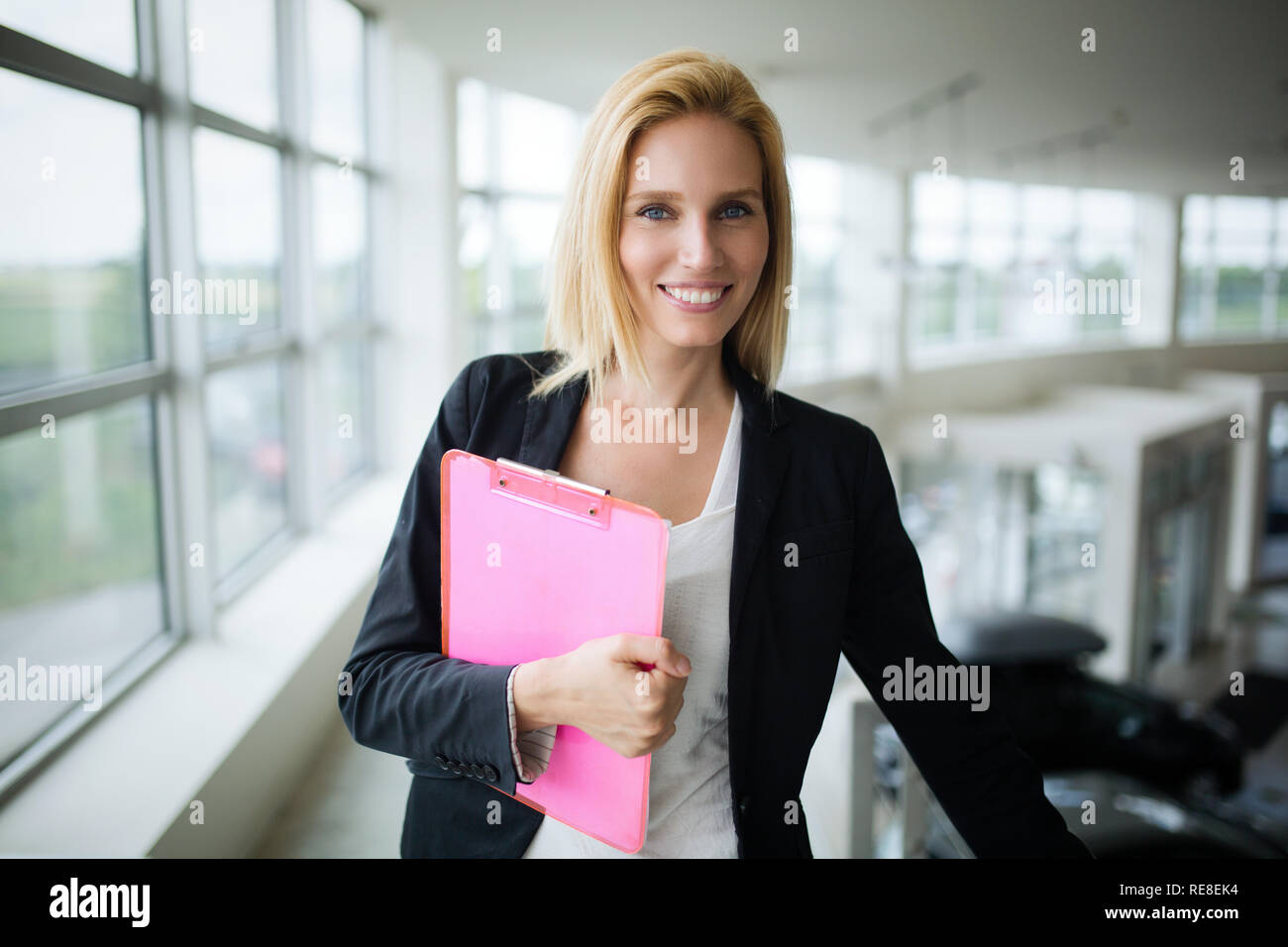 Successful smiling business woman at work holding documents, standing