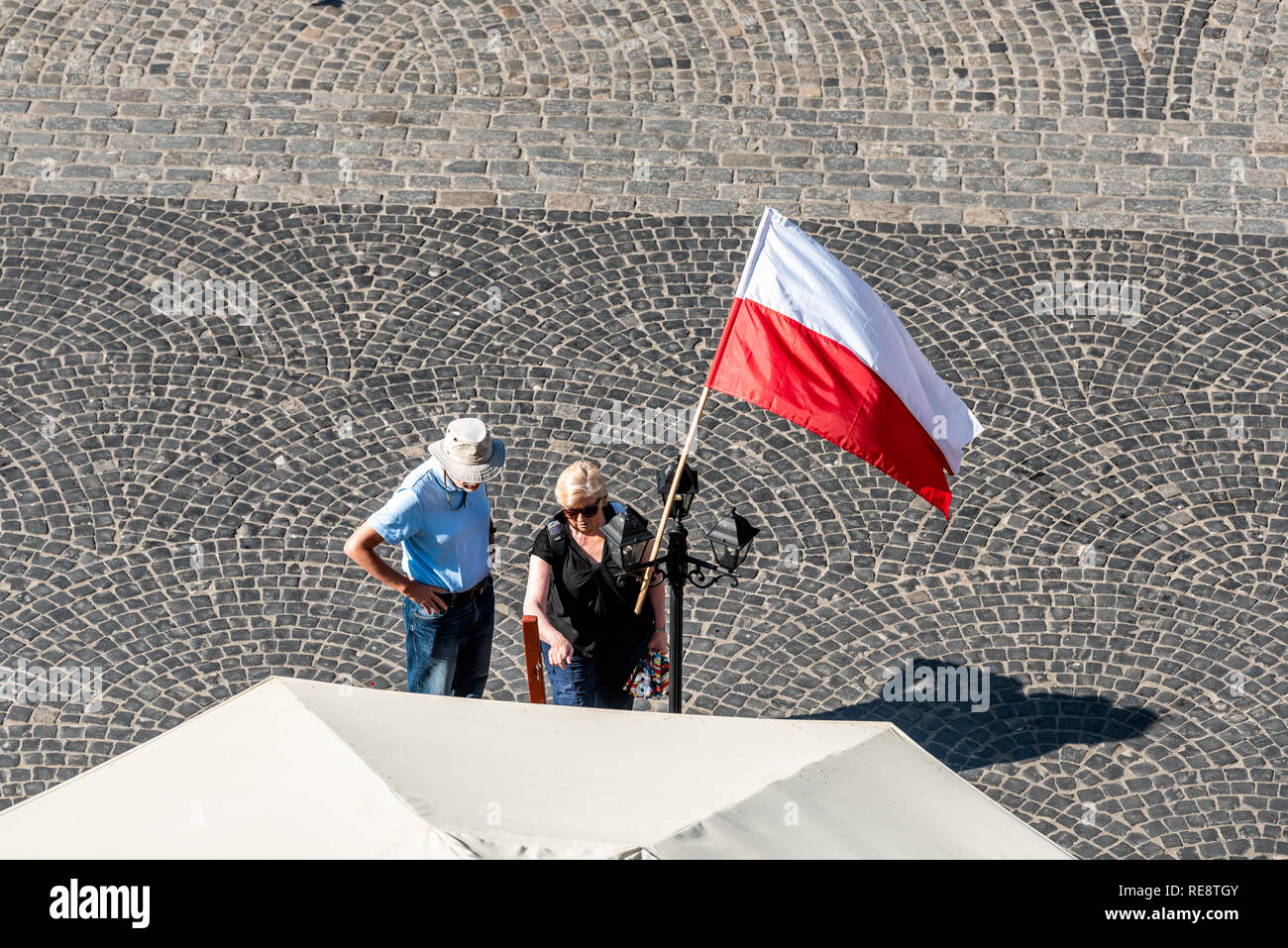 Warsaw, Poland - August 22, 2018: Old town market square with historic cobblestone street during sunny summer day high angle view of red Polish flag a Stock Photo
