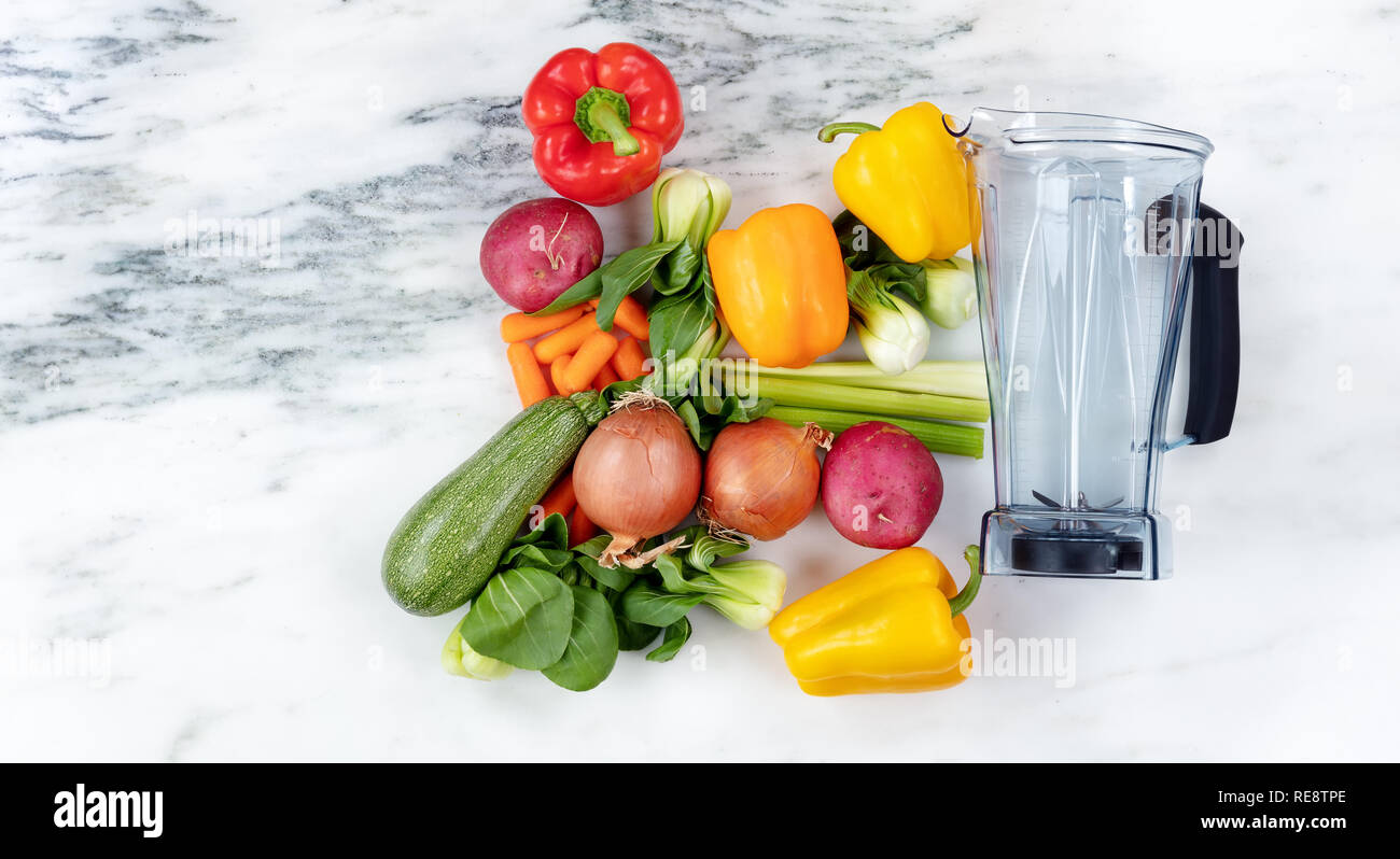 Raw organic vegetables and blender on marble stone background for