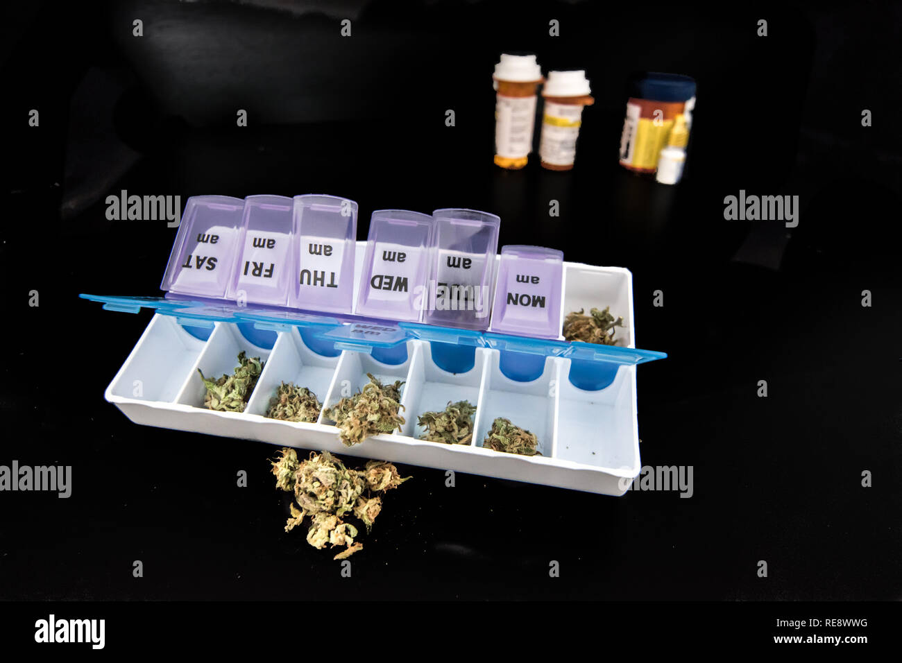 Medical Marijuana on Black Table with Pharmaceutical Drugs in Background Stock Photo