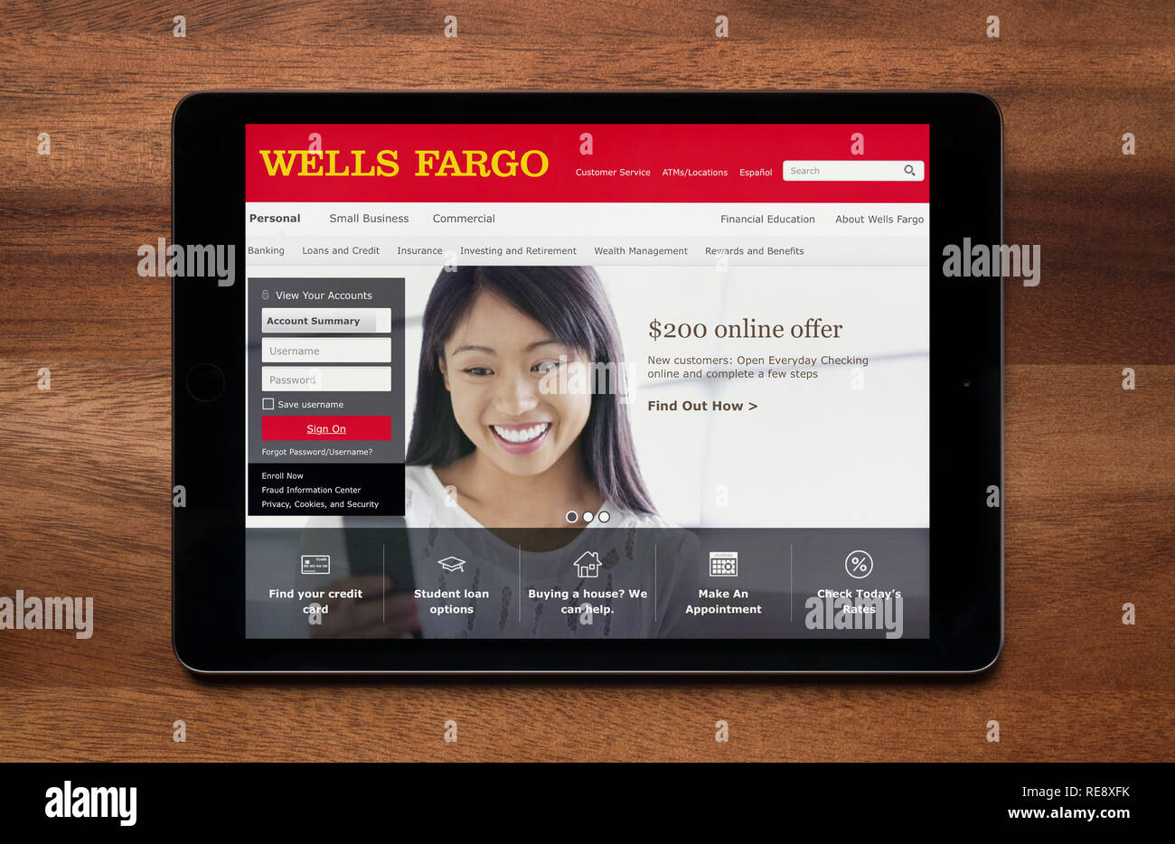 The website of Wells Fargo is seen on an iPad tablet, which is resting on a wooden table (Editorial use only). Stock Photo