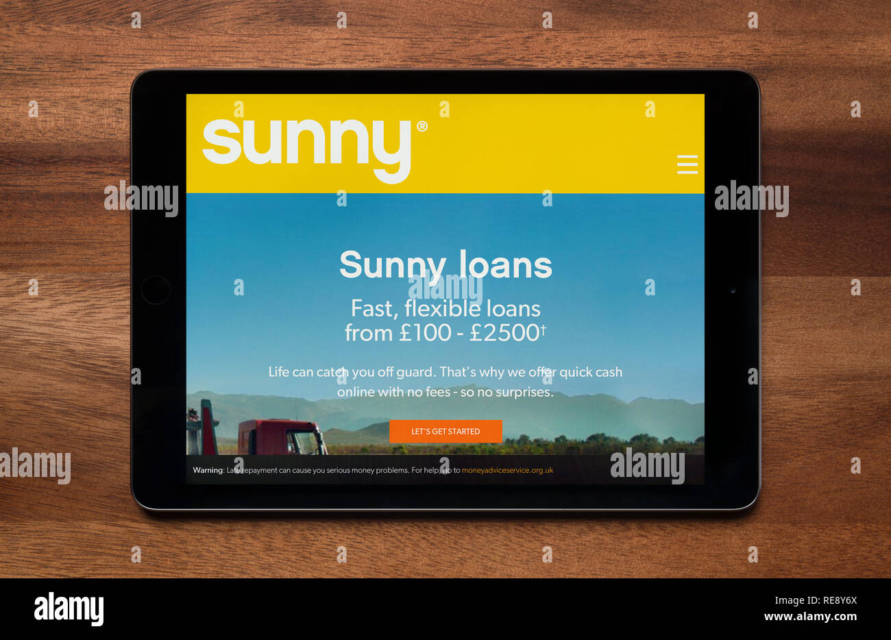 The website of Sunny Loans is seen on an iPad tablet, which is resting on a wooden table (Editorial use only). Stock Photo