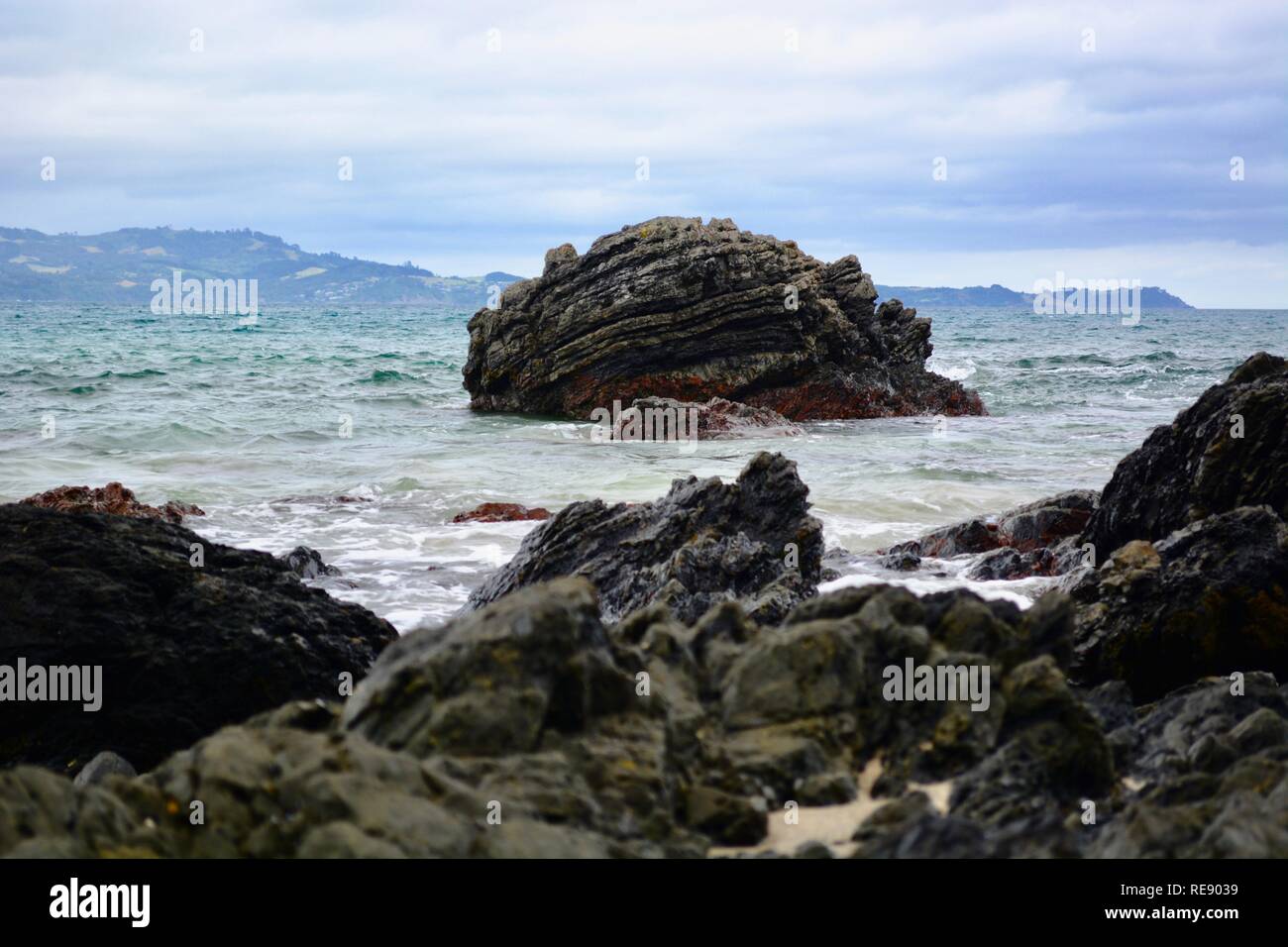 Seashores of New Zealand; beautiful seascape and bright blue ocean. Rocky foreground with clear and colourful waves. Stock Photo