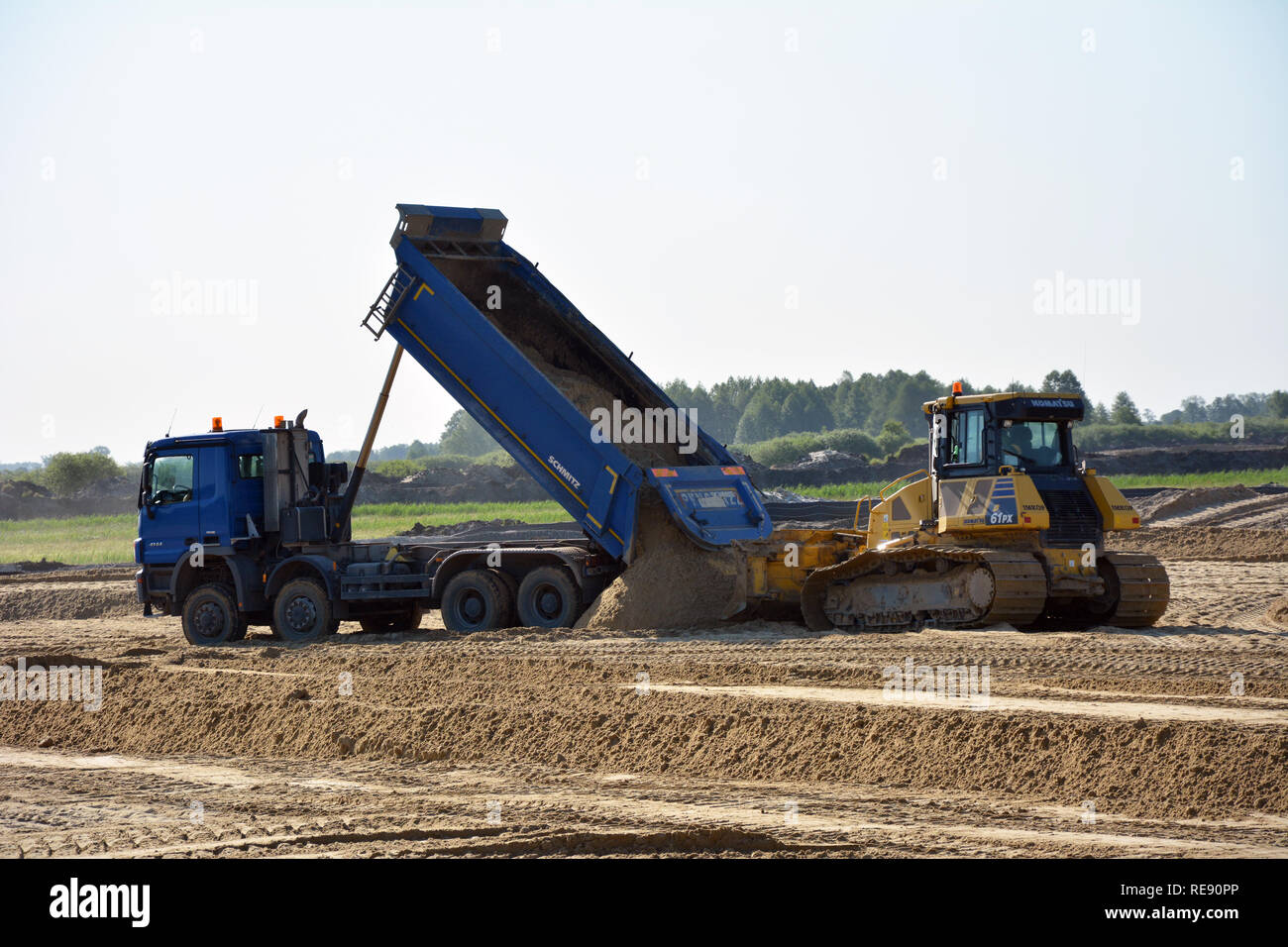 RYNARZEWO, KUJAWSKO-POMORSKIE/POLAND - MAY 25, 2018 - S5 construction site - dark blue tipper discharging a load of sand, yellow caterpillar earth mov Stock Photo