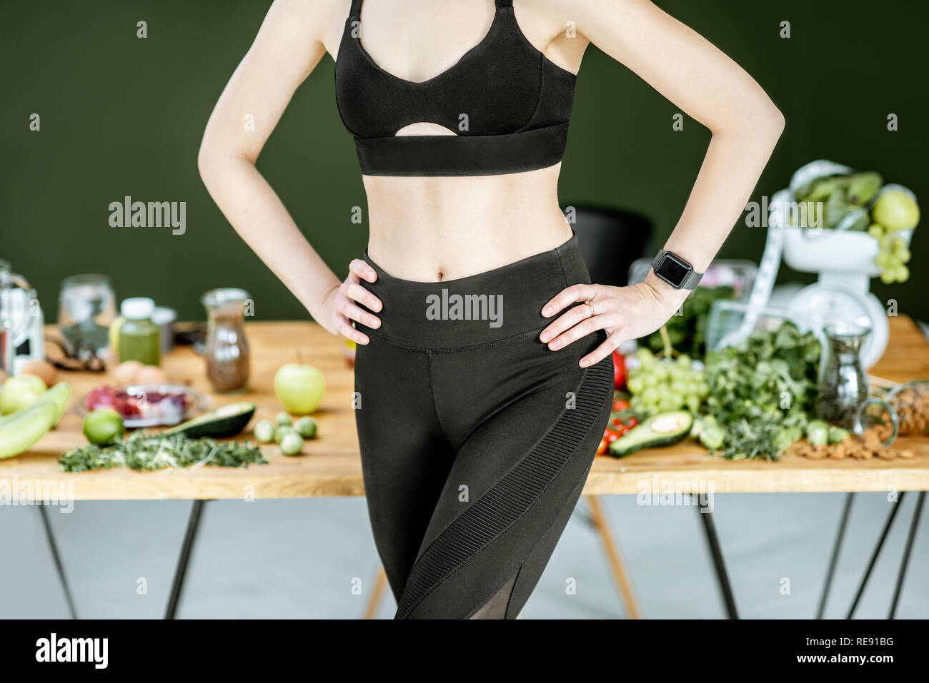 Women's athletic body in sportswear with healthy food on the background. Healthy eating and sports lifestyle concept Stock Photo
