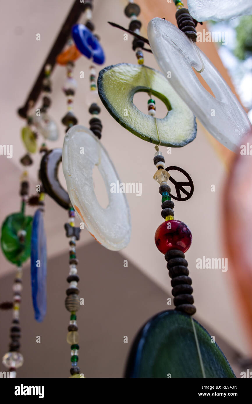 Close up of various wind chimes made out of recycled plastic, glass and metal objects with a peace symbol Stock Photo