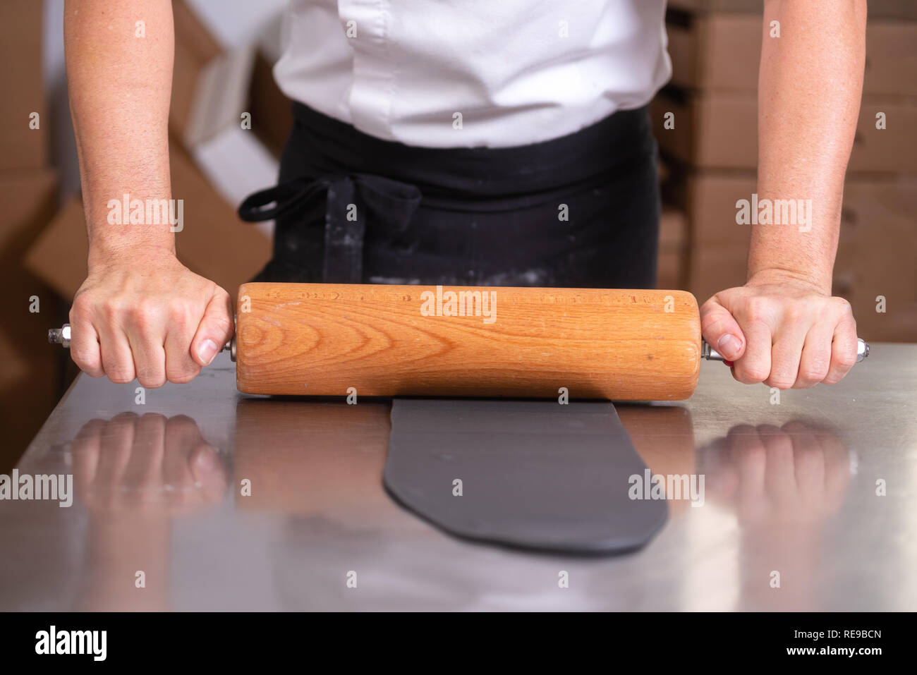 Confectioner using rolling pin preparing fondant for cake decorating . Stock Photo