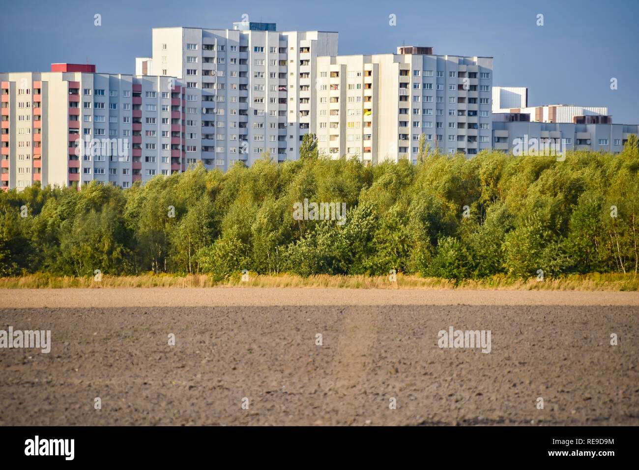View over a harvested field to the satellite city Gropiusstadt in Berlin-Neukölln illuminated by the sun. Stock Photo