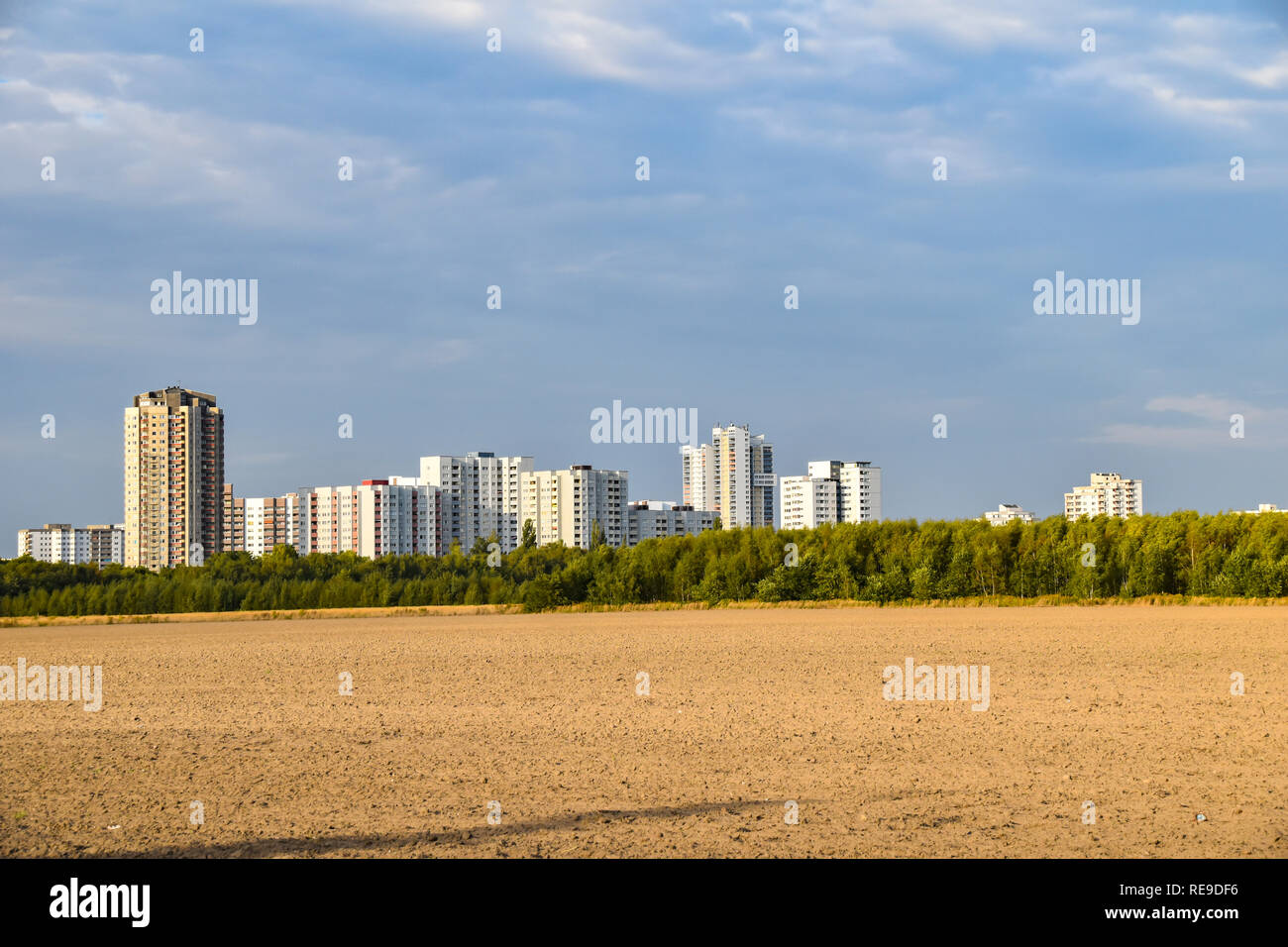 View over a harvested field to the satellite city Gropiusstadt in Berlin-Neukölln illuminated by the sun. Stock Photo