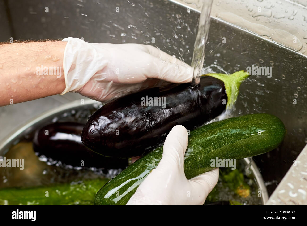 Black eggplant rinsing by stream of tap water. Cleaning eggplant in