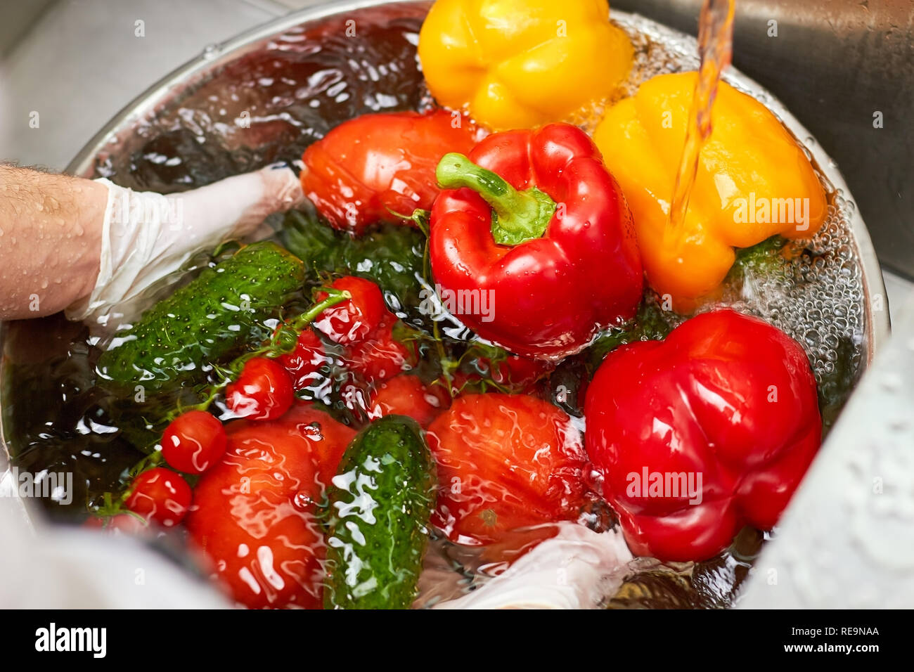 Many vegetables sinking in a bowl of water. Chef dipping vegetables
