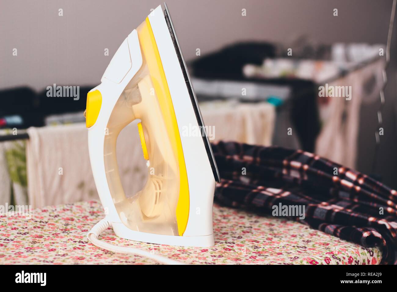 Iron yellow shade stand on the ironing board with patterns of small
