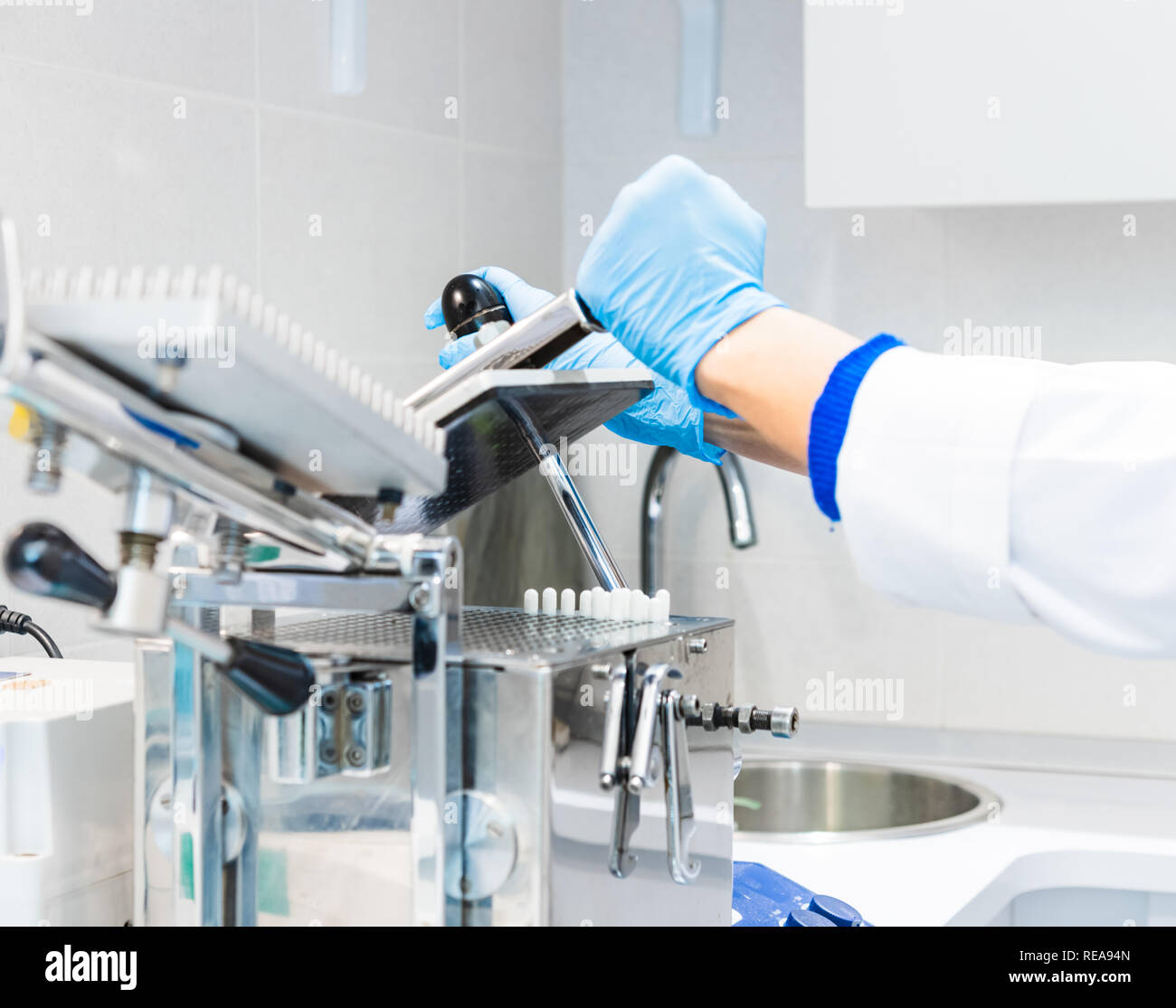 Close up of human hands with glove handling encapsulator machine in pharmacy laboratory Stock Photo