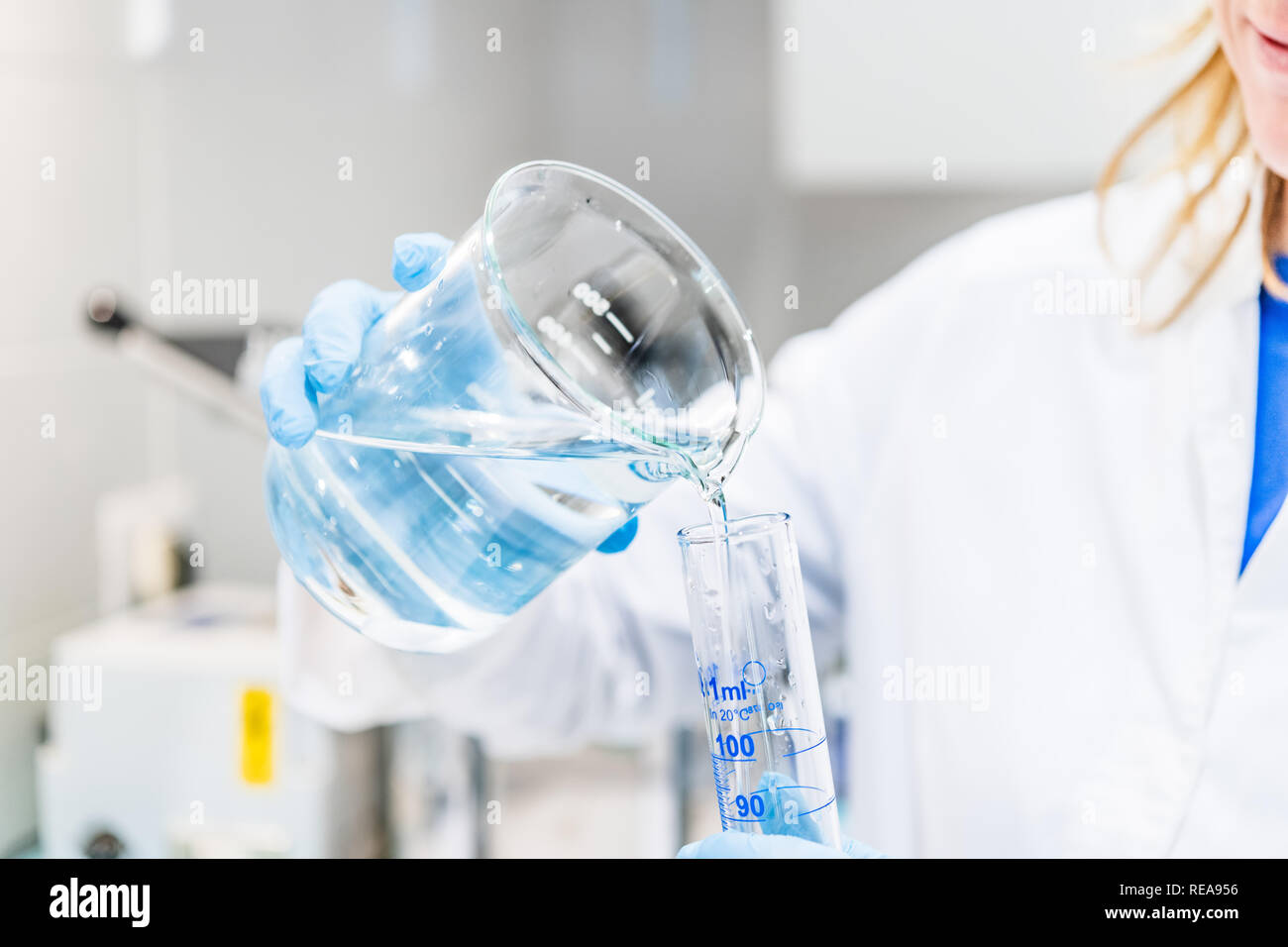 Close up of human hands holding glass recipients with liquid in chemist