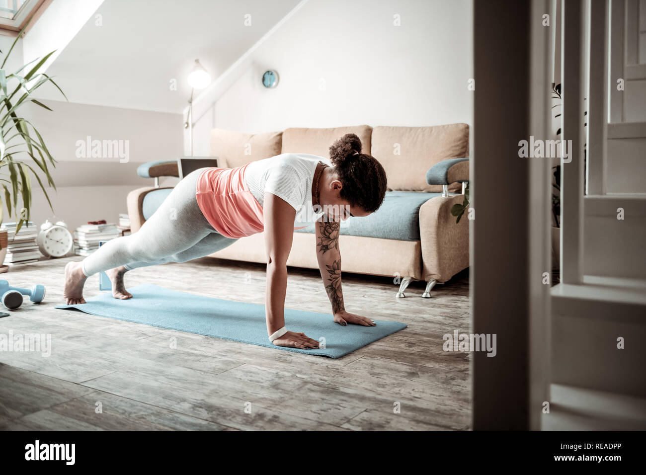 Concentrated young lady doing push-ups during training Stock Photo