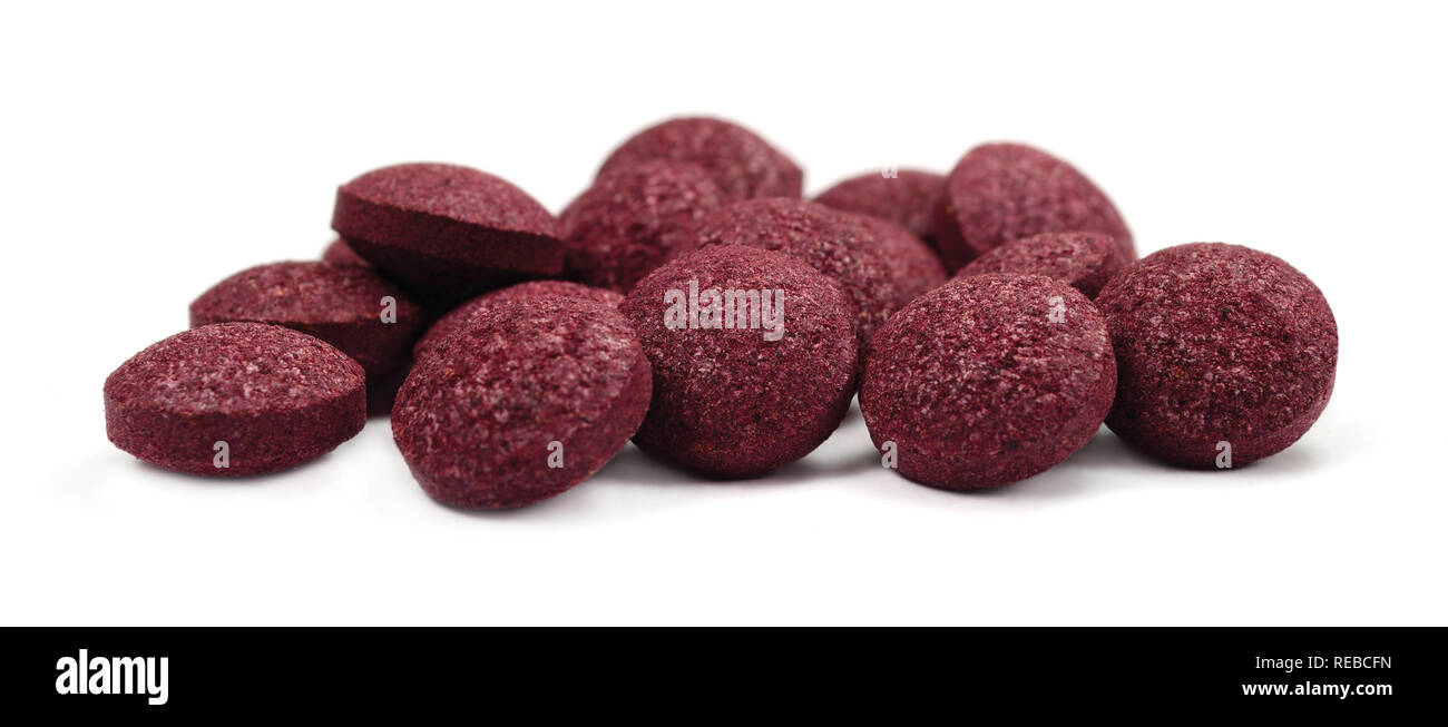 Black chokeberry fruit pills, large detailed isolated tablets macro closeup, organic raw aronia melanocarpa berry fruits pill pile, burgundy colored Stock Photo