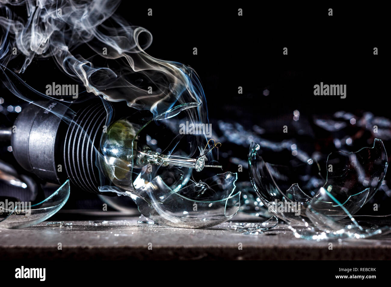 amazing explosion of a burning light bulb with splinters and smoke on a black background with a
