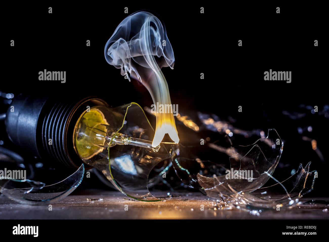 amazing explosion of a burning light bulb with splinters and smoke on a ...