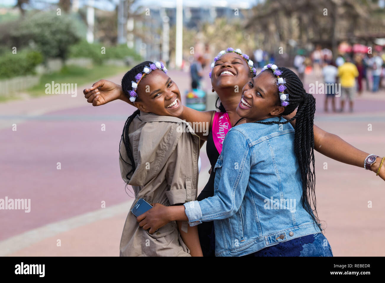 Durban, South Africa - January 07th, 2019: Three beautiful black young women laughing and celebrating a birthday outdoors in Durban, South Africa. Stock Photo
