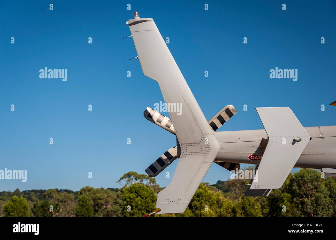 Detail of the tail of a modern military helicopter against trees and a blue sky Stock Photo