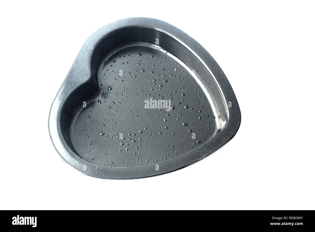 Metal heart shaped baking dish isolated on white background. Oil droplets Stock Photo
