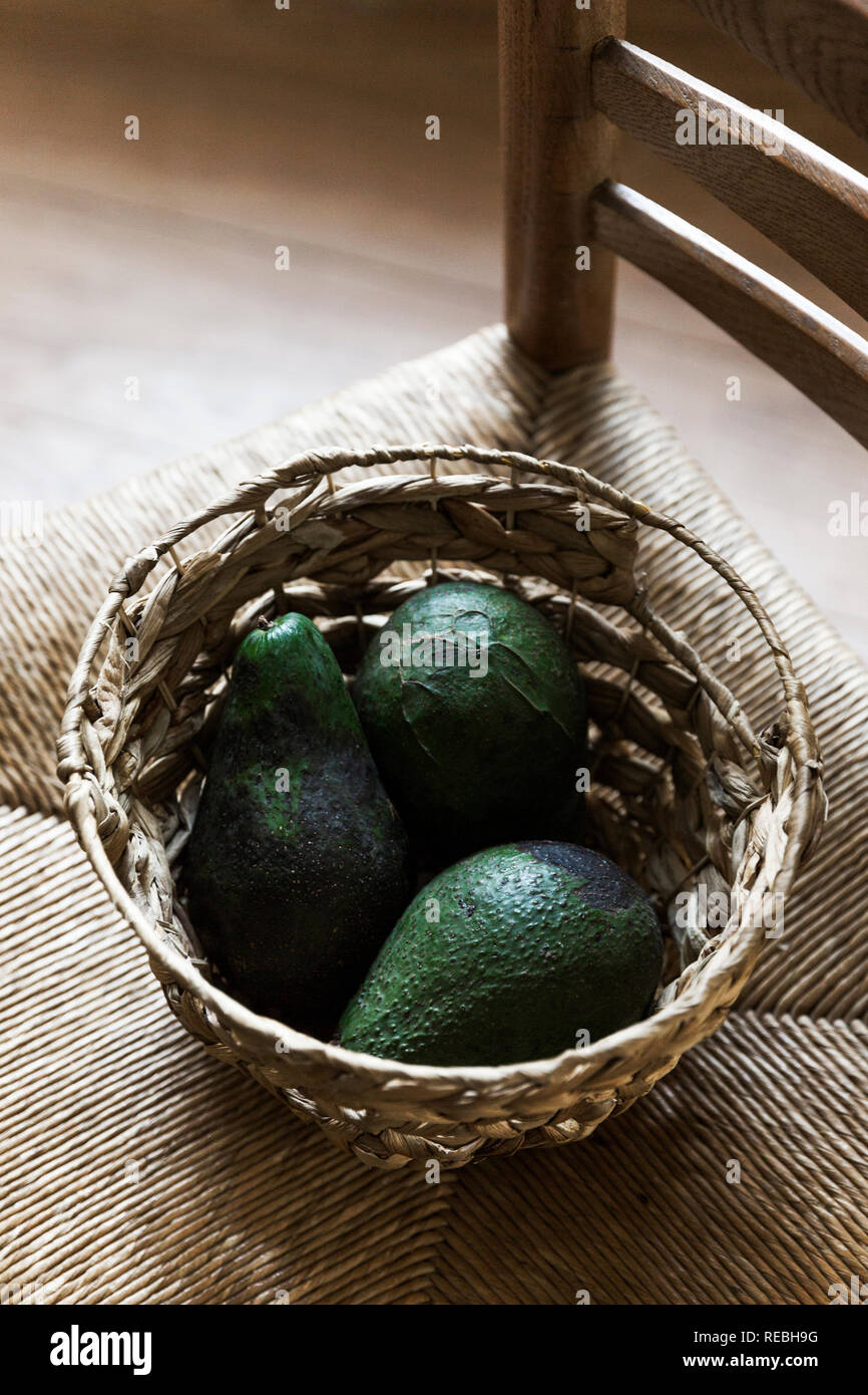 Overhead shot of four green avocados in a rectangular shaped straw fruit  basket Stock Photo - Alamy