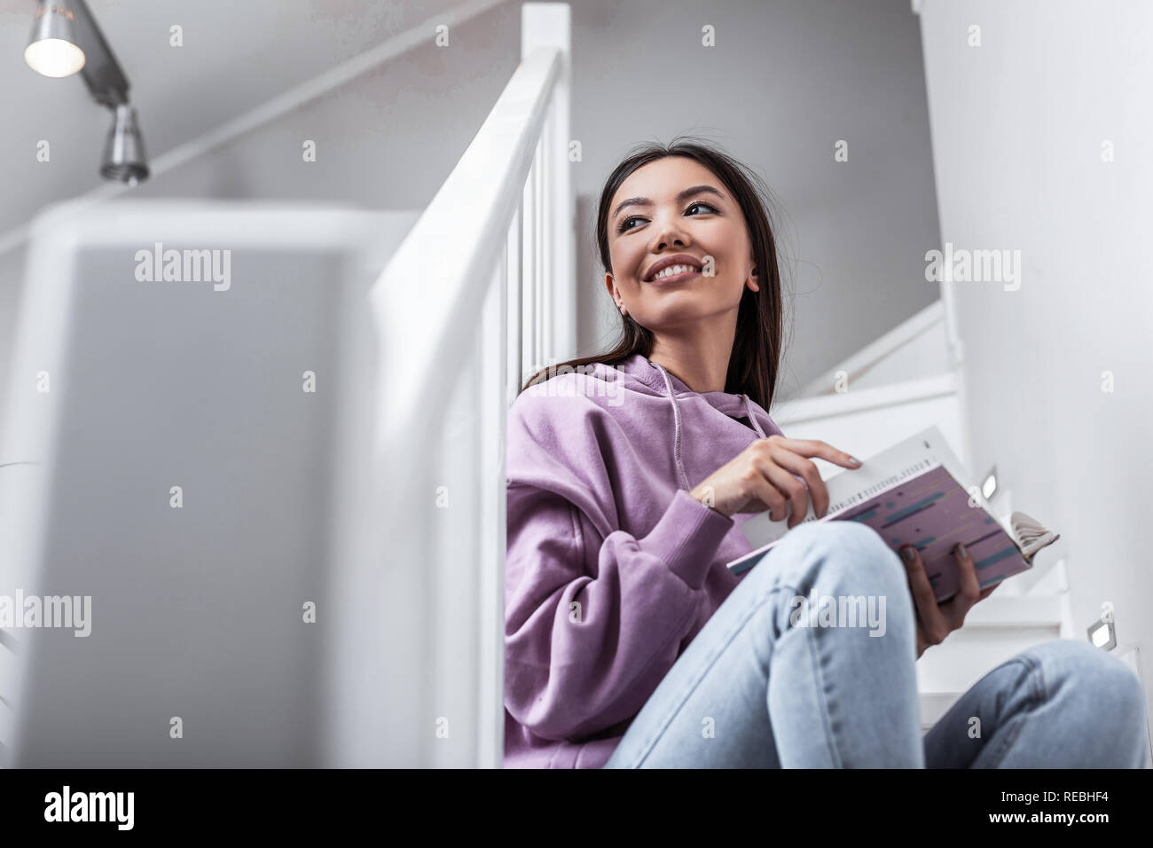 Dark-eyed woman feeling involved in reading breathtaking book Stock Photo