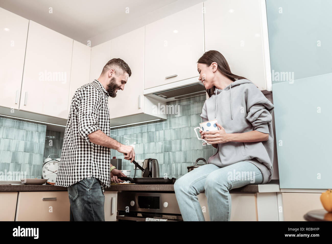 Bearded man feeling joyful while making dinner for wife Stock Photo