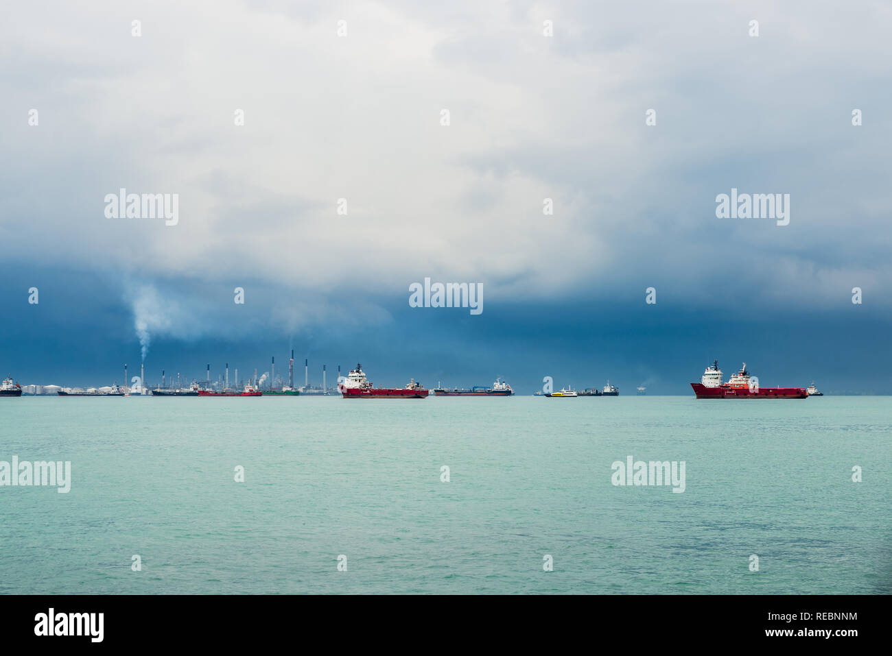 View of the Singapore Strait from Sentosa Island. Ships, industrial landscape and stormy weather. Stock Photo