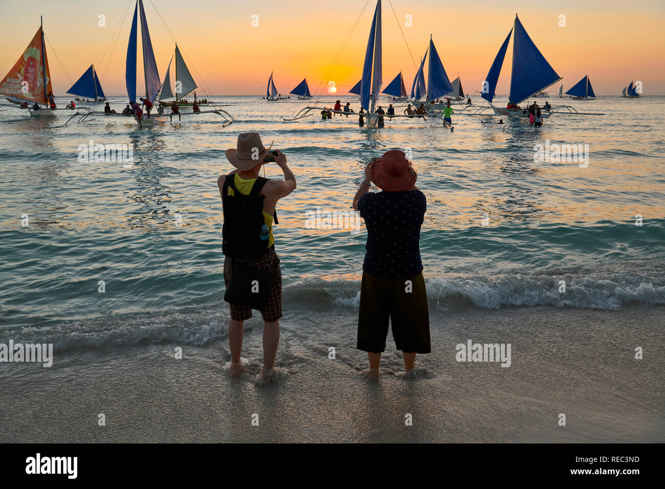 Older Asian couple enjoying the the sunset along the White Beach on Boracay Island, Philippines Stock Photo