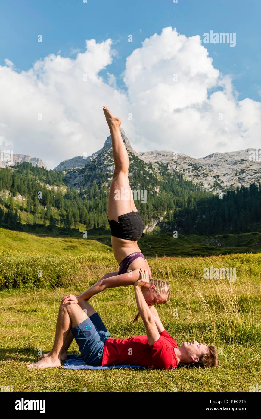 Young woman and young man doing acro yoga, mountain landscape, Berchtesgaden National Park, Berchtesgadener Land, Upper Bavaria Stock Photo