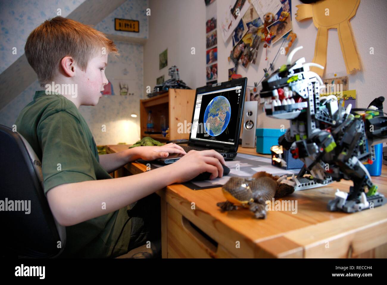 Boy, 11, working with his computer at home in his bedroom at a desk ...