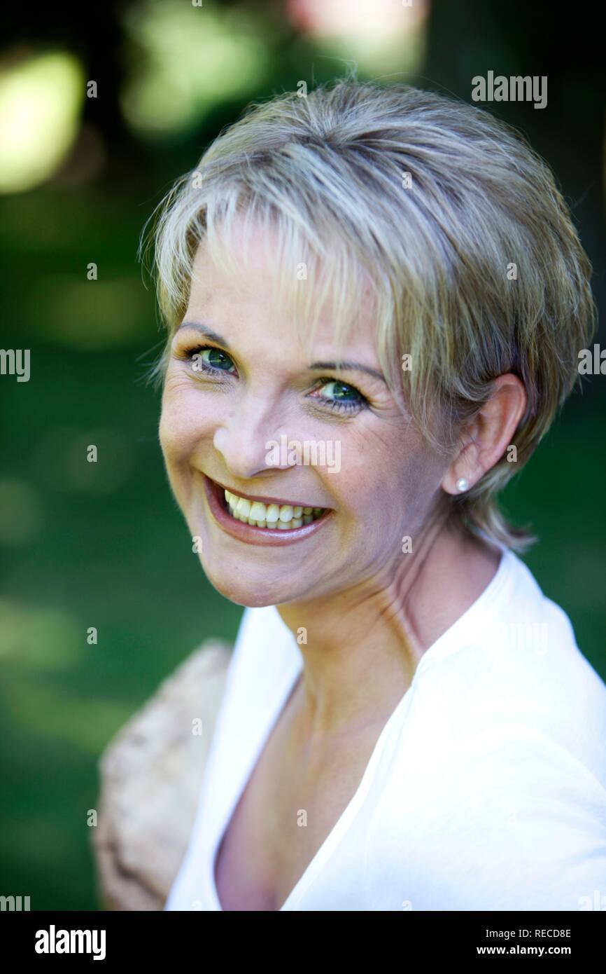 Portrait of a woman, early 40s, in the garden, looking at the camera, smiling Stock Photo