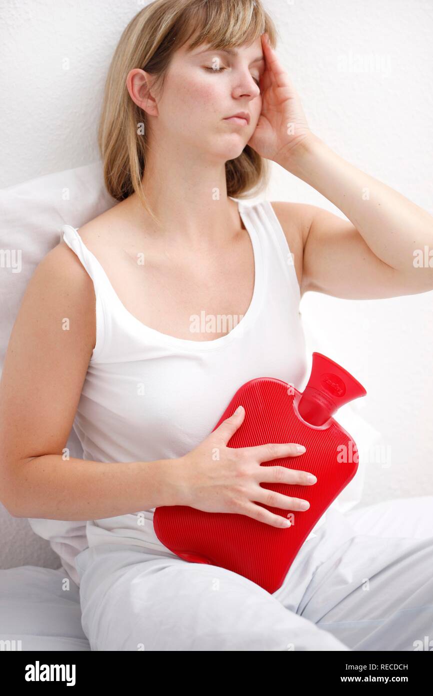 Woman has a stomachache, eases pain with a hot water bag, hot water bottle  Stock Photo - Alamy