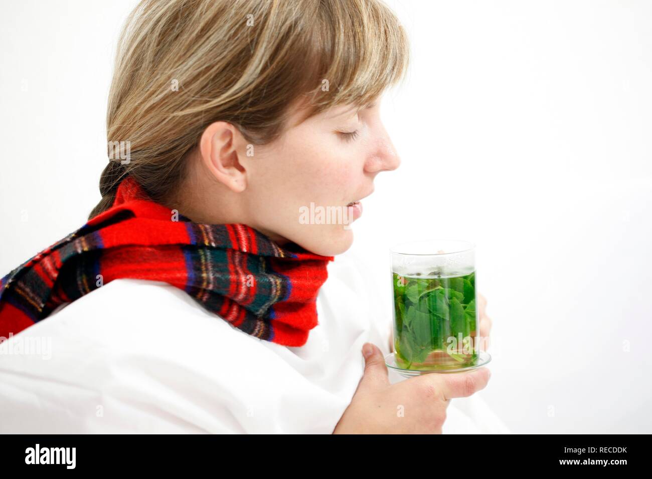 A young woman with a sore throat and a cold in bed, with a scarf