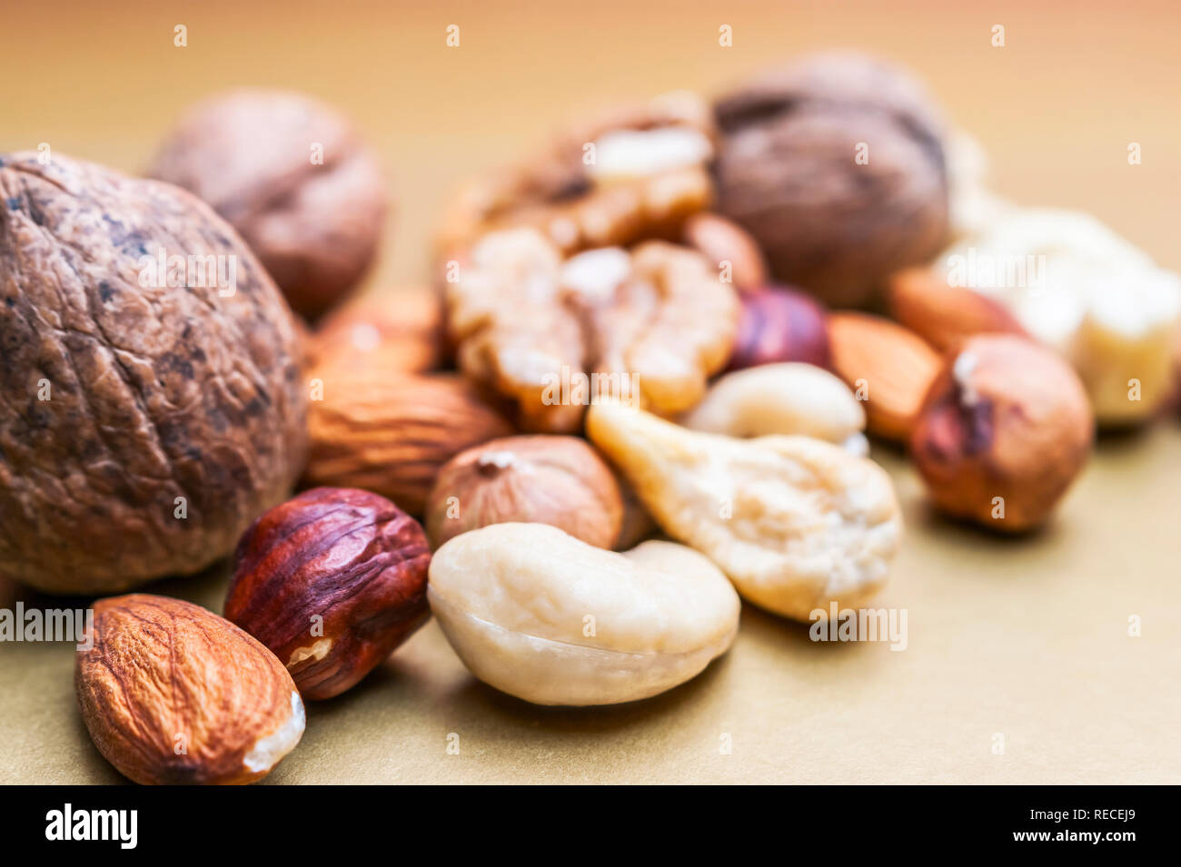 Almonds, Hazelnuts, Cashew Nuts and Whole Walnuts on Golden Background. Healthy Organic Snack, Breakfast, Food Ingredients Stock Photo