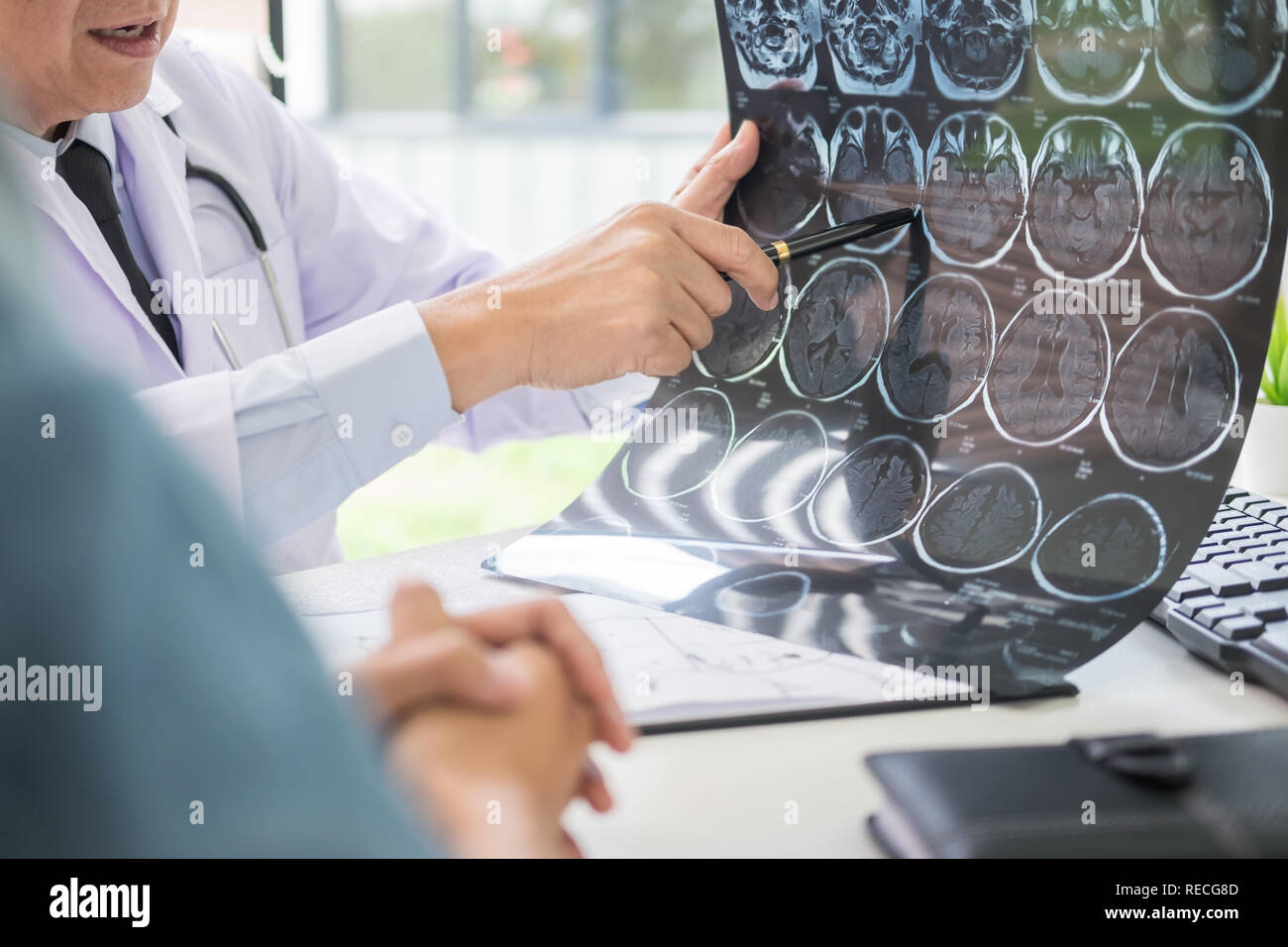 doctor analyzing a scan or x-ray film or explains a CT scan thoughtful ...