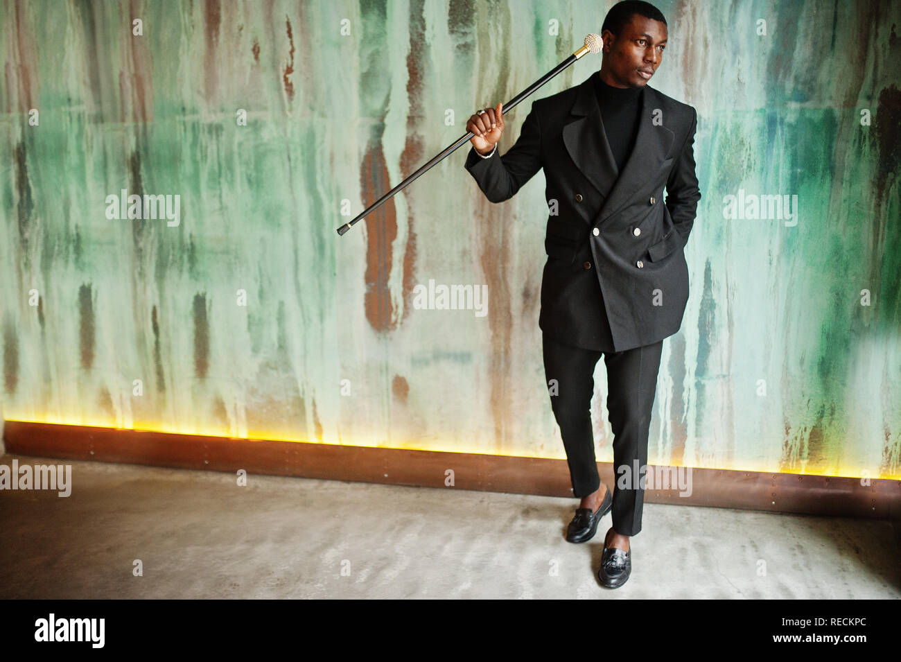 Stylish african american gentleman in elegant black jacket, holding