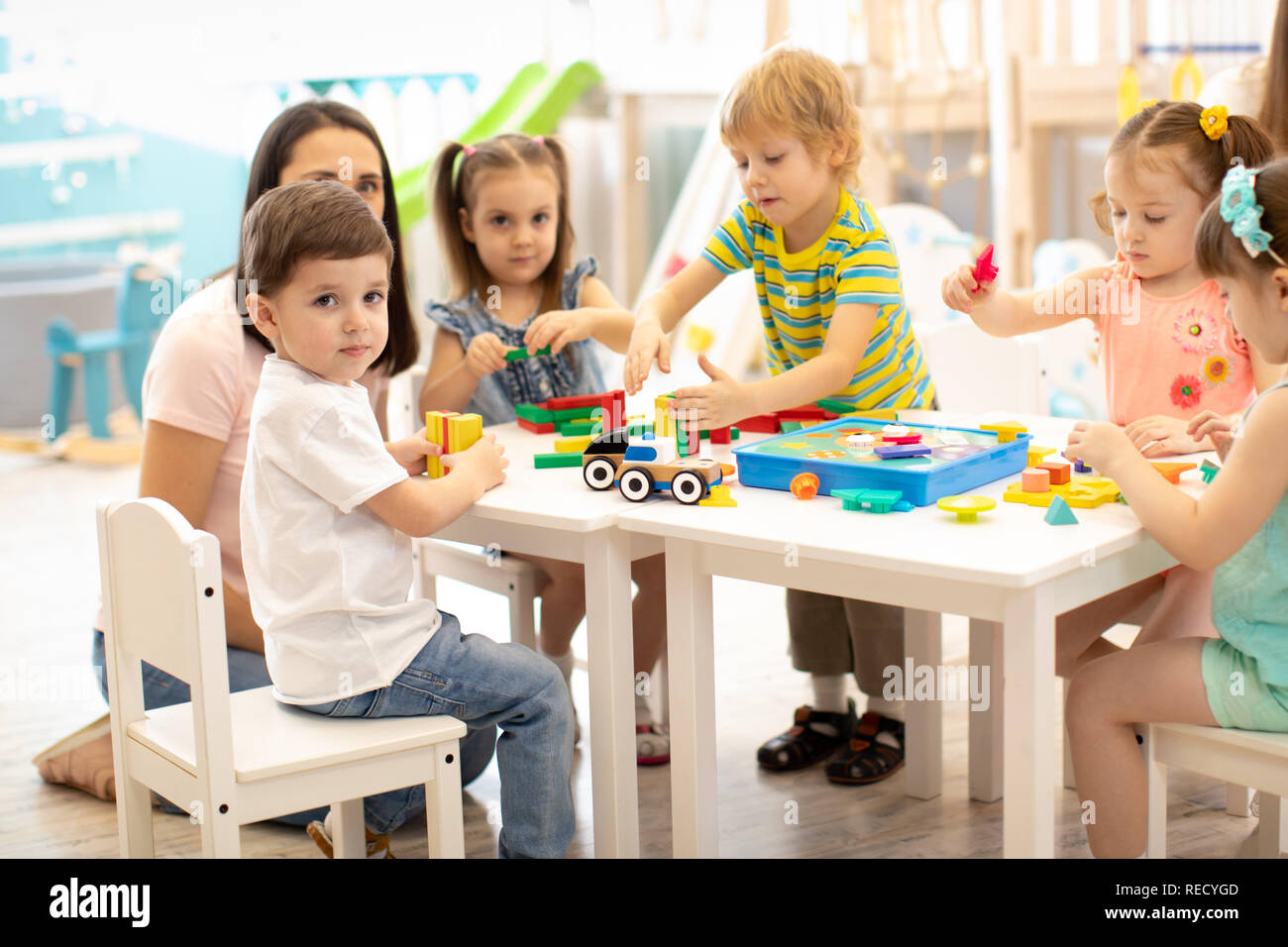 Kindergarten children play color toys with teacher in playroom at ...