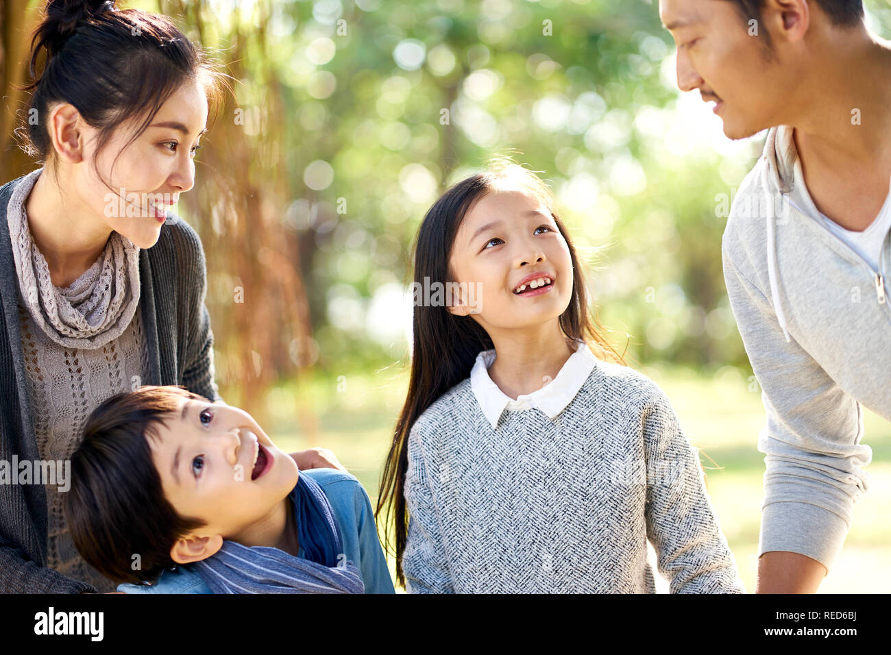 asian family with two children having fun exploring woods in a park. Stock Photo