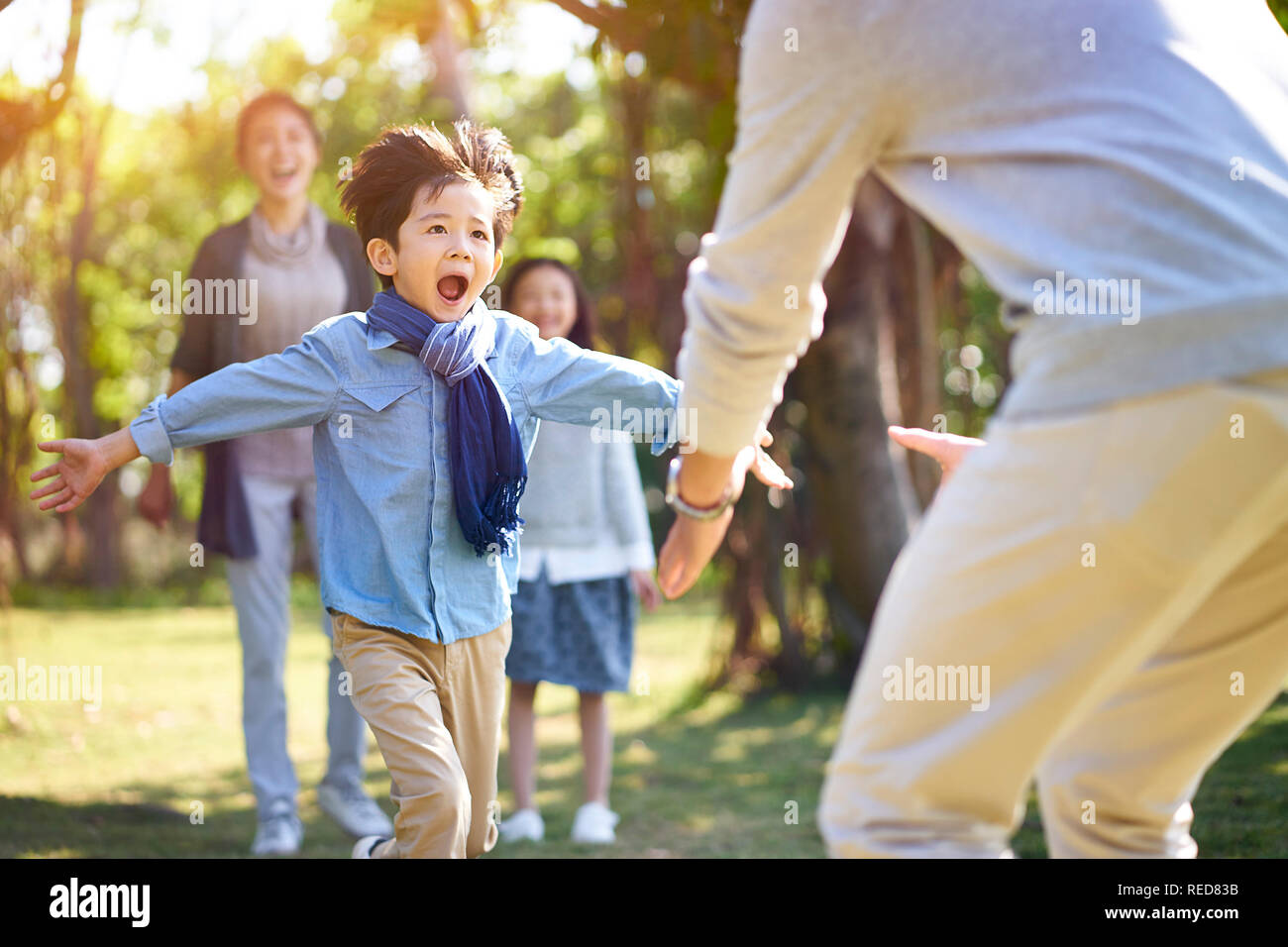 asian little boy son running towards father's embrace. Stock Photo