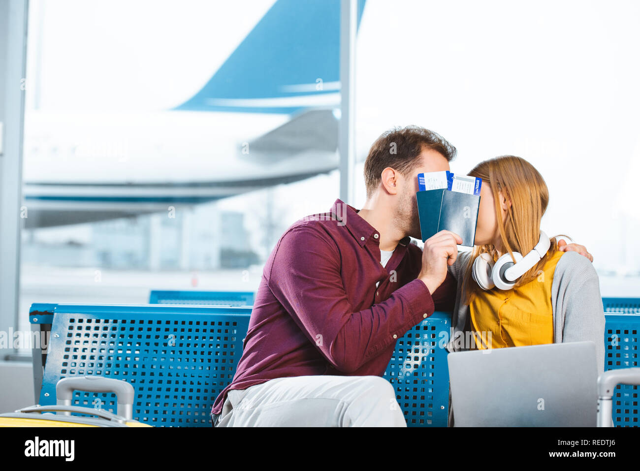 boyfriend and girlfriend covering faces with passports in airport lounge Stock Photo