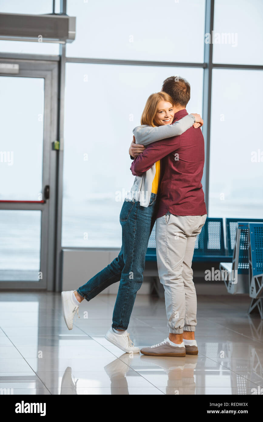 attractive woman hugging boyfriend in waiting hall Stock Photo - Alamy