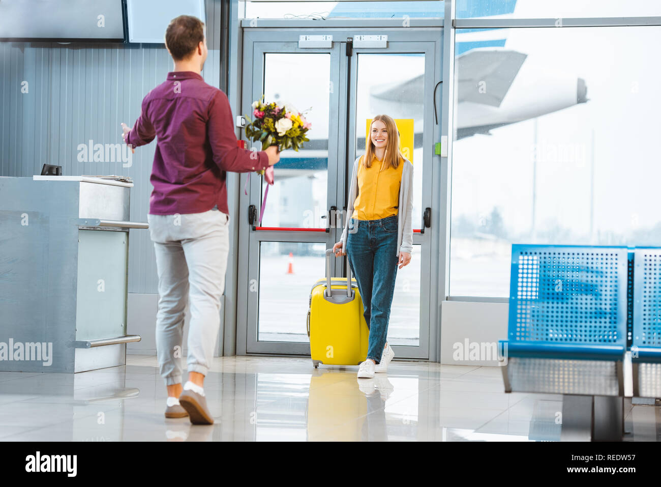 back view of boyfriend with flowers meeting happy girlfriend with