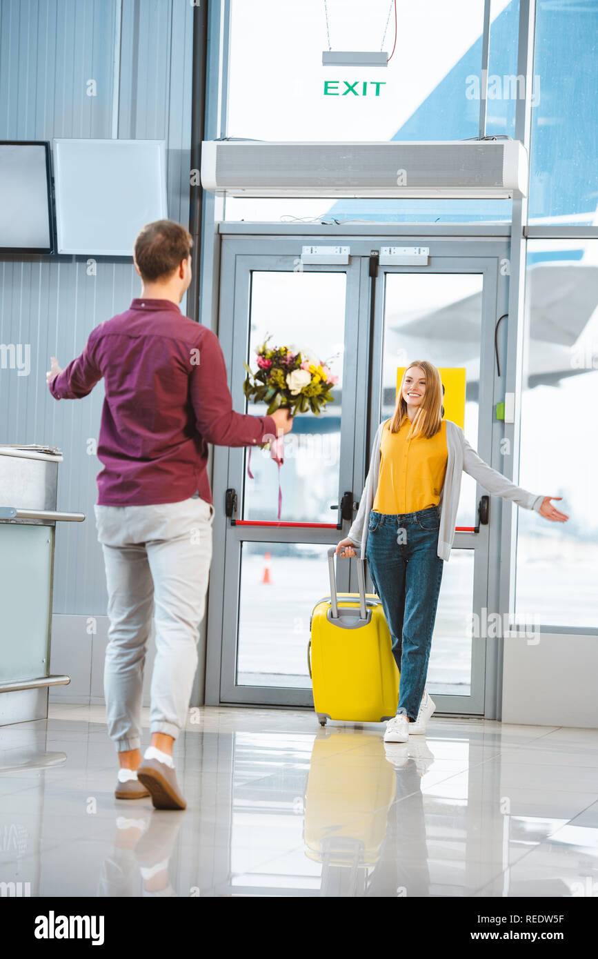 back view of boyfriend with flowers meeting beautiful girlfriend with