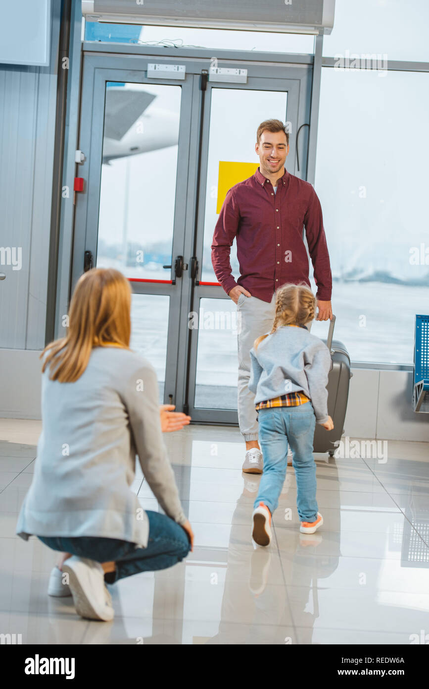 daughter running to cheerful dad while meeting in airport Stock Photo