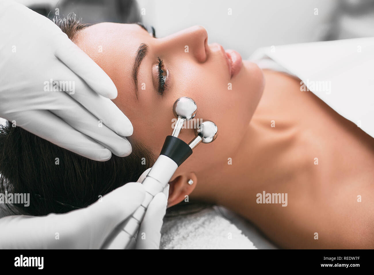 Beautiful woman receiving facial microcurrent procedure for rejuvenation skin. Stock Photo