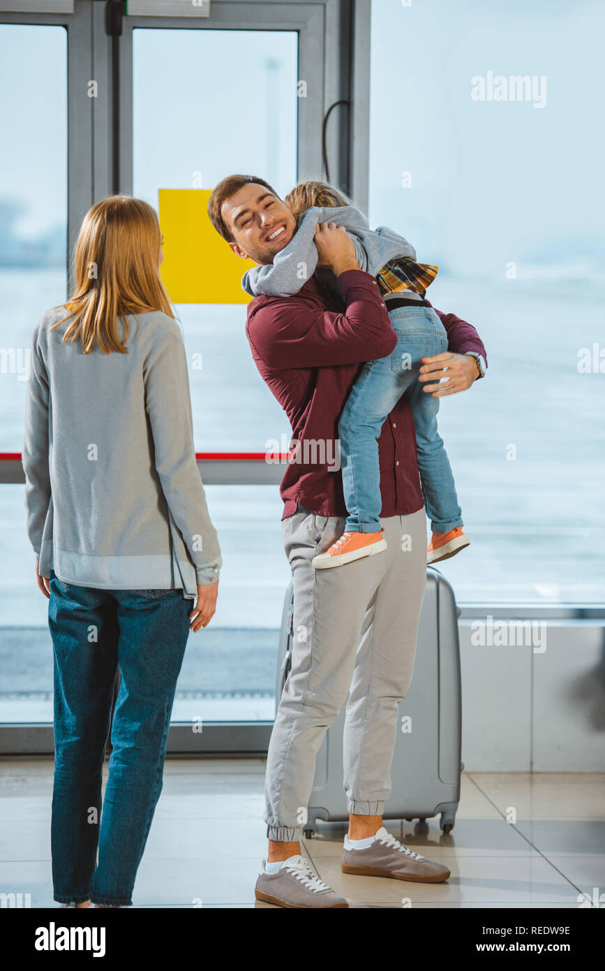happy father holding in arms daughter near wife in airport Stock Photo ...