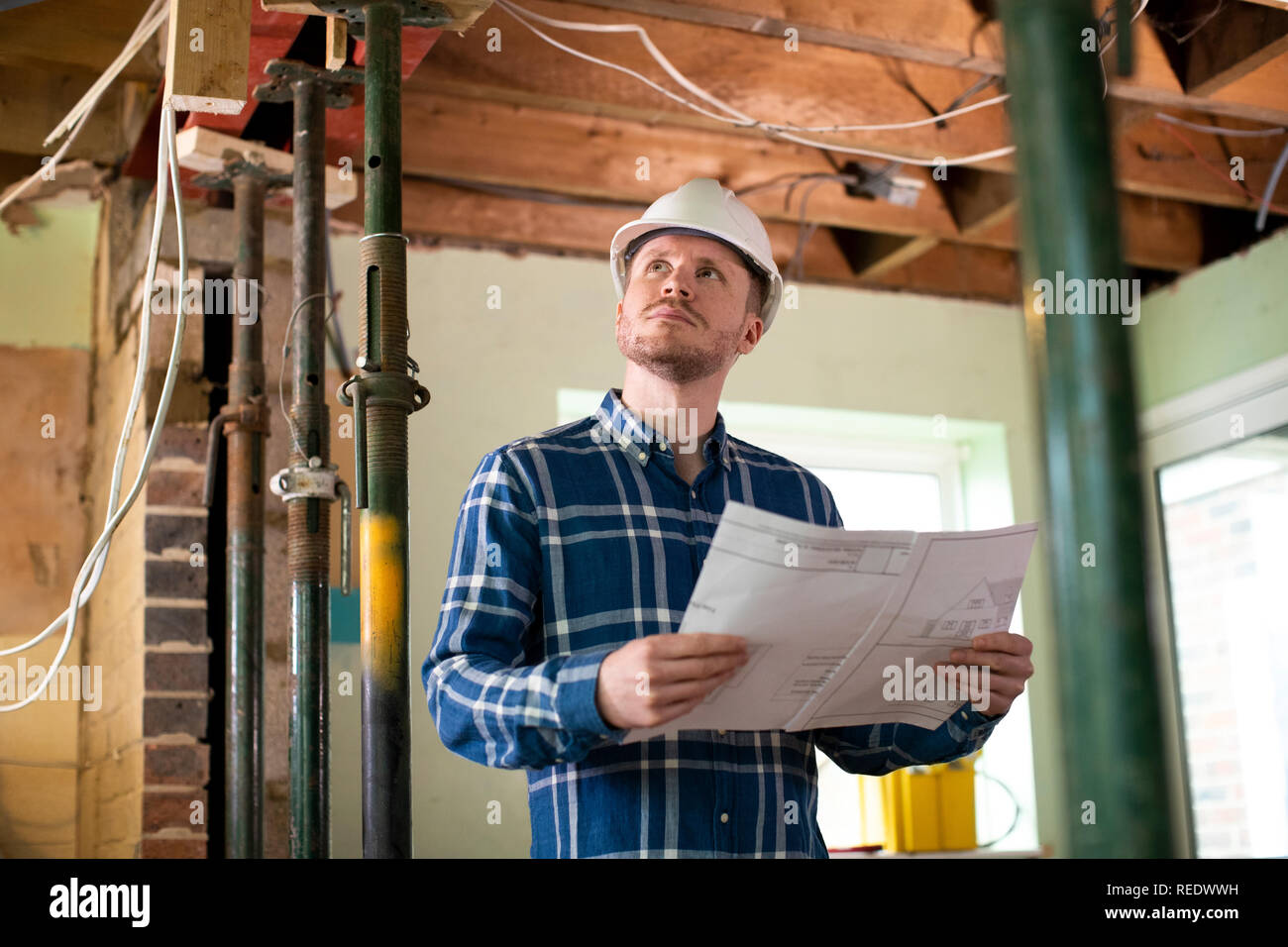 Architect Inside House Being Renovated Studying Plans Stock Photo